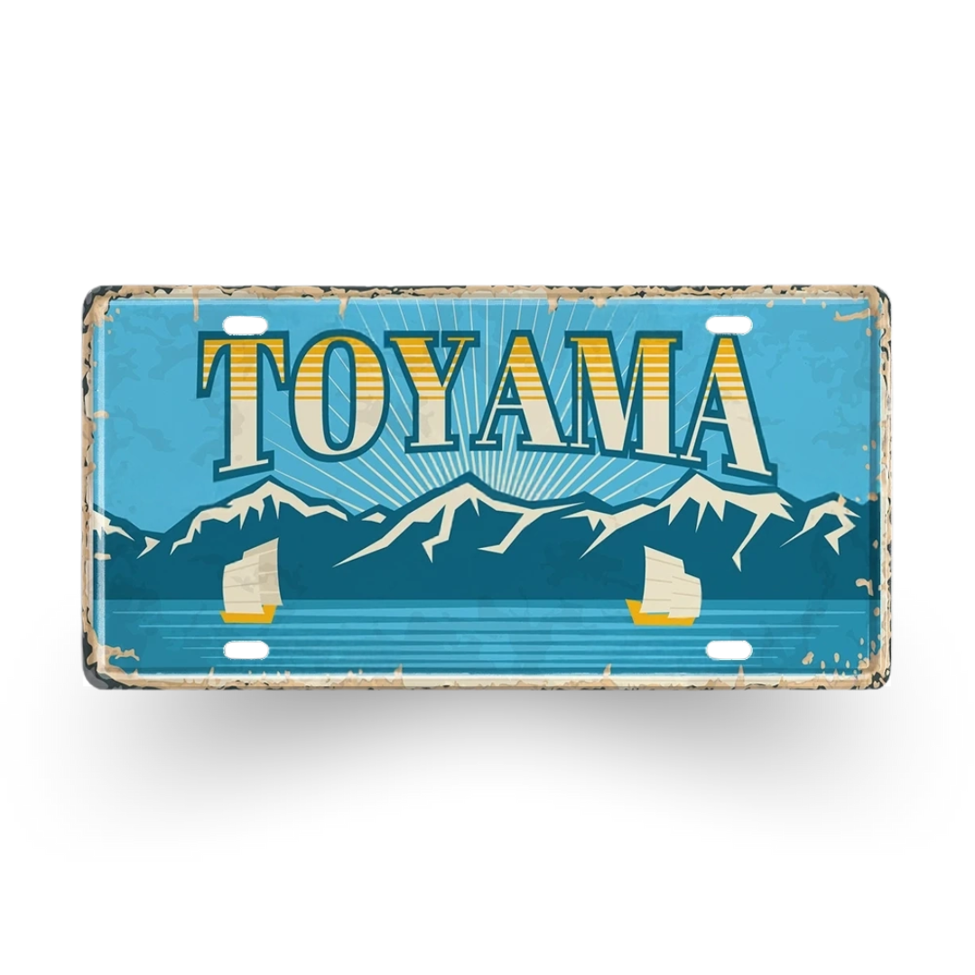 Vintage-style license plate with 'TOYAMA' text and mountain design on a blue background