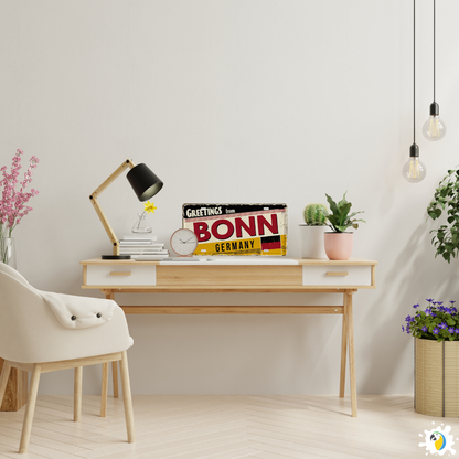 Modern home office with a desk, chair, and decorative items including a 'Greetings from Bonn, Germany' sign.
