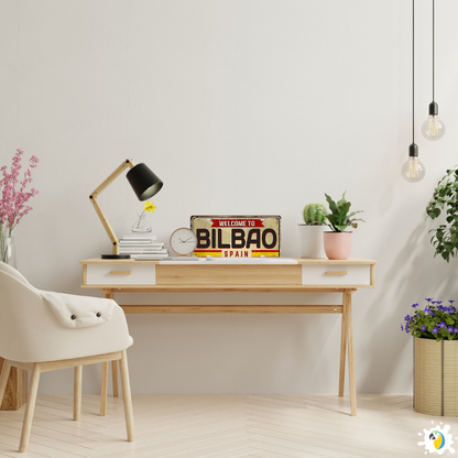 Modern home office with a desk, chair, and decorative items including a 'Welcome to Bilbao Spain' sign.
