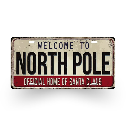 Metal sign with 'Welcome to North Pole, Official Home of Santa Claus' text on a white background