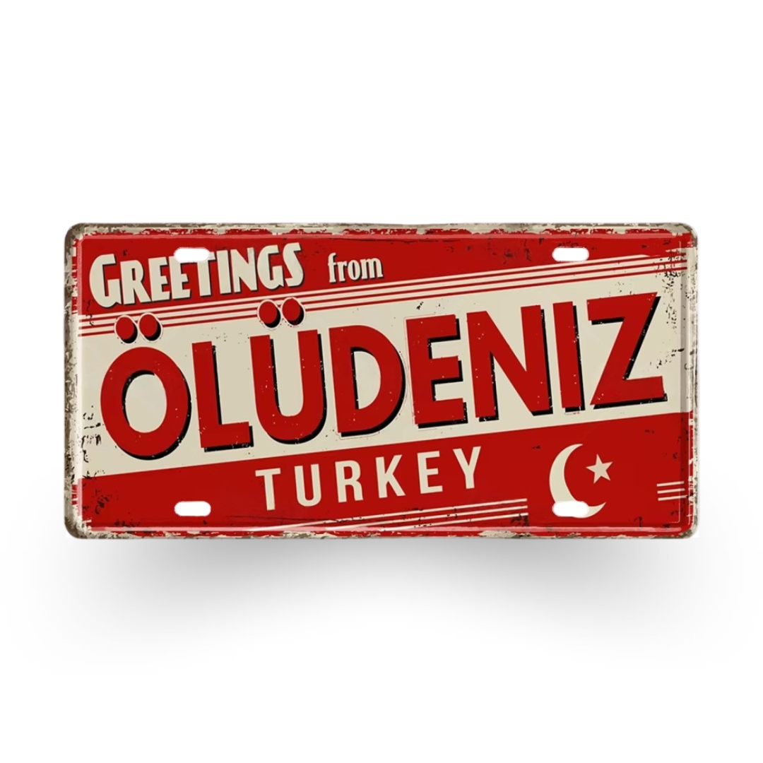 Vintage-style sign with 'Greetings from Oludeniz Turkey' text on a red and beige background.